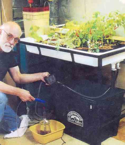 The Lee Valley modern hydroponics system is compact. The water heater and air stone are connected to the air pump via clear plastic tubing, the submersible water pump is connected to the inlet on the water table's bottom by black plastic tubing. Mylar film on the back wall reflects light energy back onto plants.